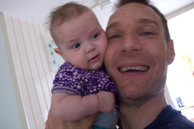 Een baby die liefdevol wordt vastgehouden door een man.